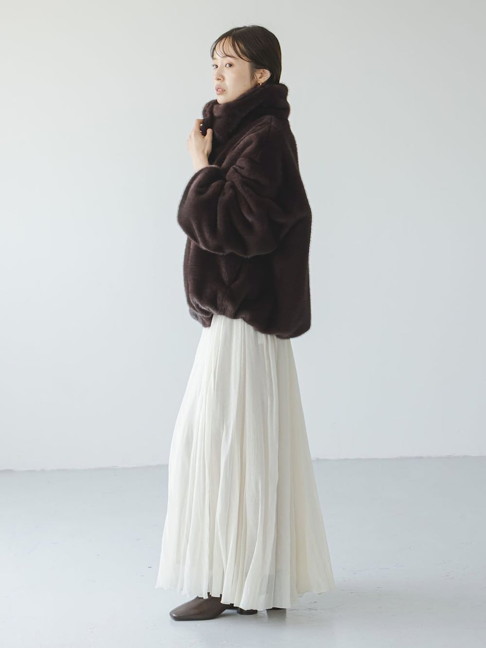 ブラウン系のその他アウター、ホワイト系のスカート、ベージュ系のショルダーバッグを着用したレディースの冬コーディネートの2枚目の写真