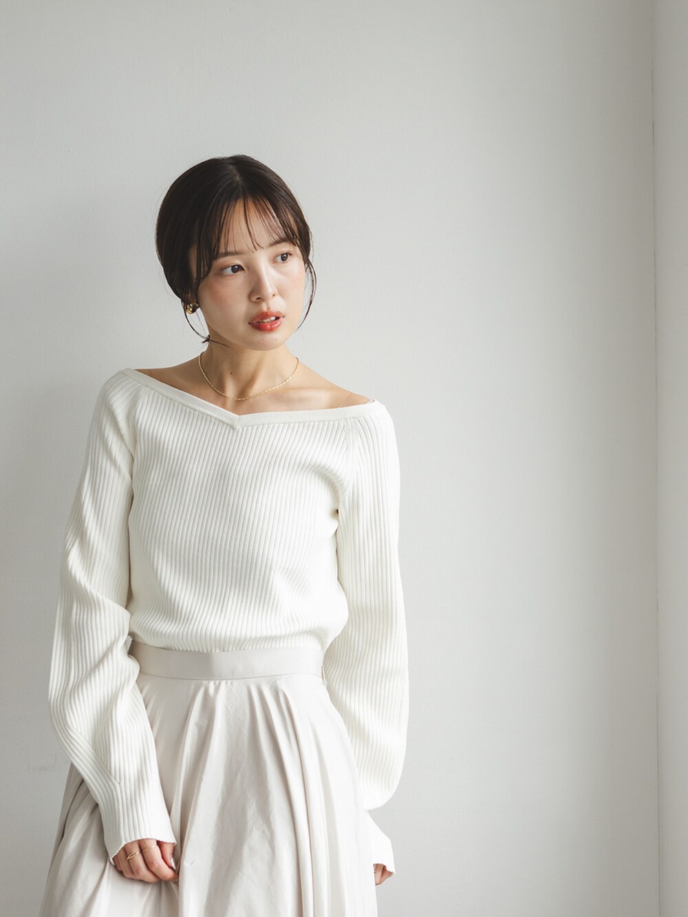 ホワイト系のニット/セーター、ベージュ系のスカート、ブラウン系のローファーを着用したレディースの秋コーディネートの2枚目の写真