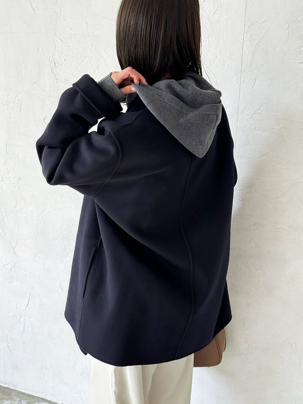 ブルー系のチェスターコート、グレー系のニット/セーター、ホワイト系のスラックスを着用したレディースの秋コーディネートの4枚目の写真