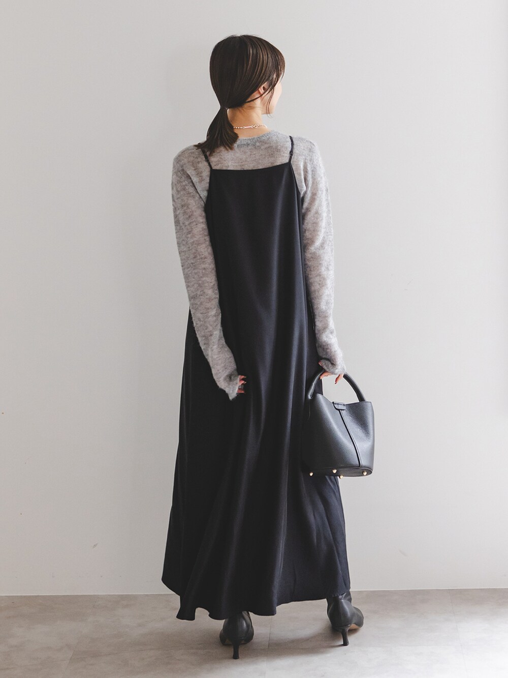 ブラック系のワンピース、ブラック系のブーツ、ブラック系のショルダーバッグを着用したレディースの冬コーディネートの3枚目の写真