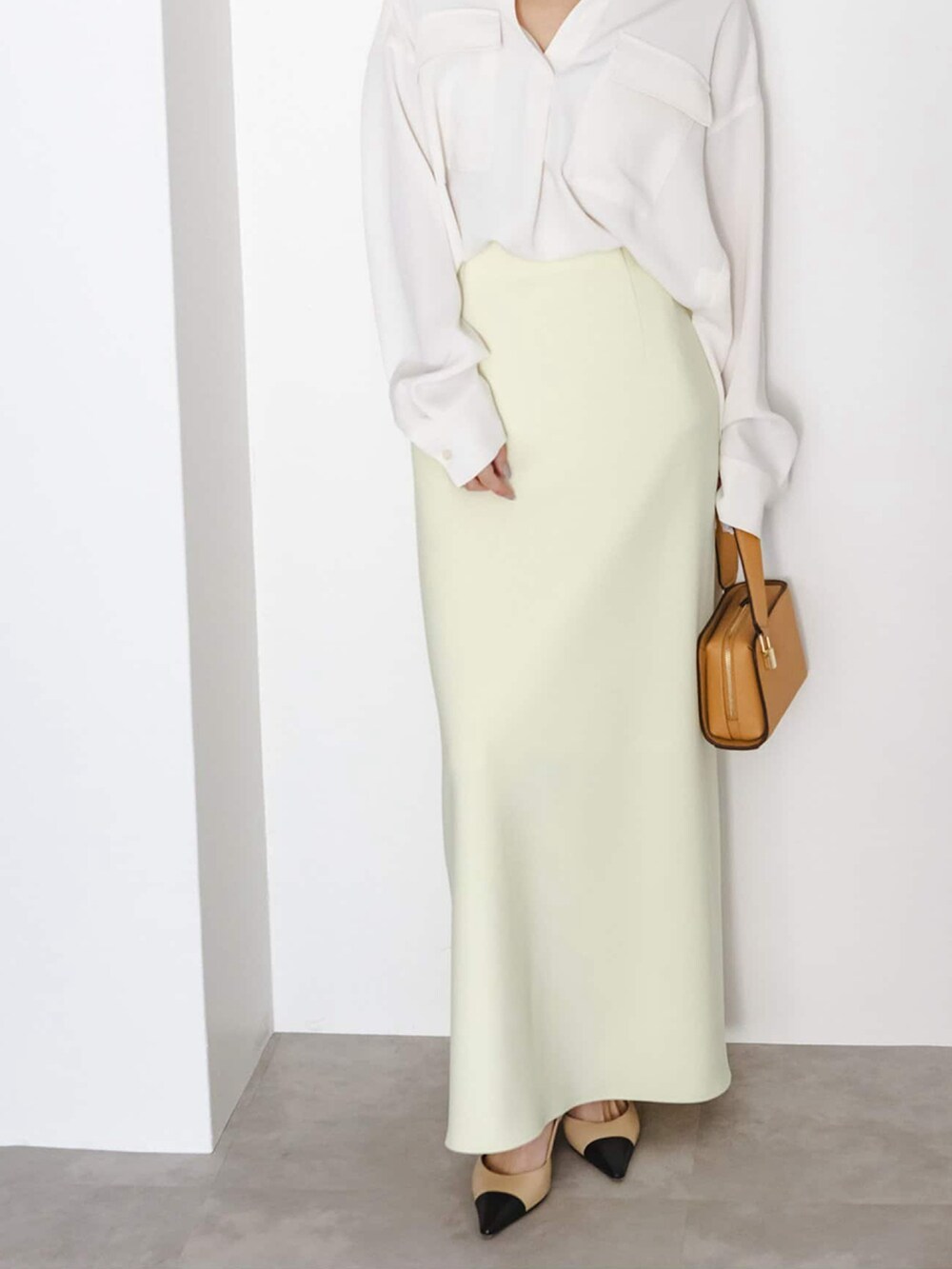 イエロー系のスカート、ホワイト系のシャツ/ブラウス、イエロー系のショルダーバッグを着用したレディースの冬コーディネートの3枚目の写真