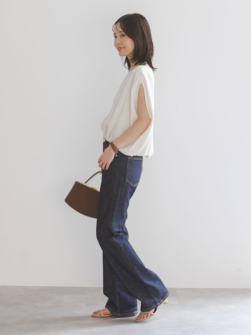 ブルー系のデニムパンツ、ホワイト系のシャツ/ブラウス、ブラウン系のハンドバッグを着用したレディースの夏コーディネートの2枚目の写真