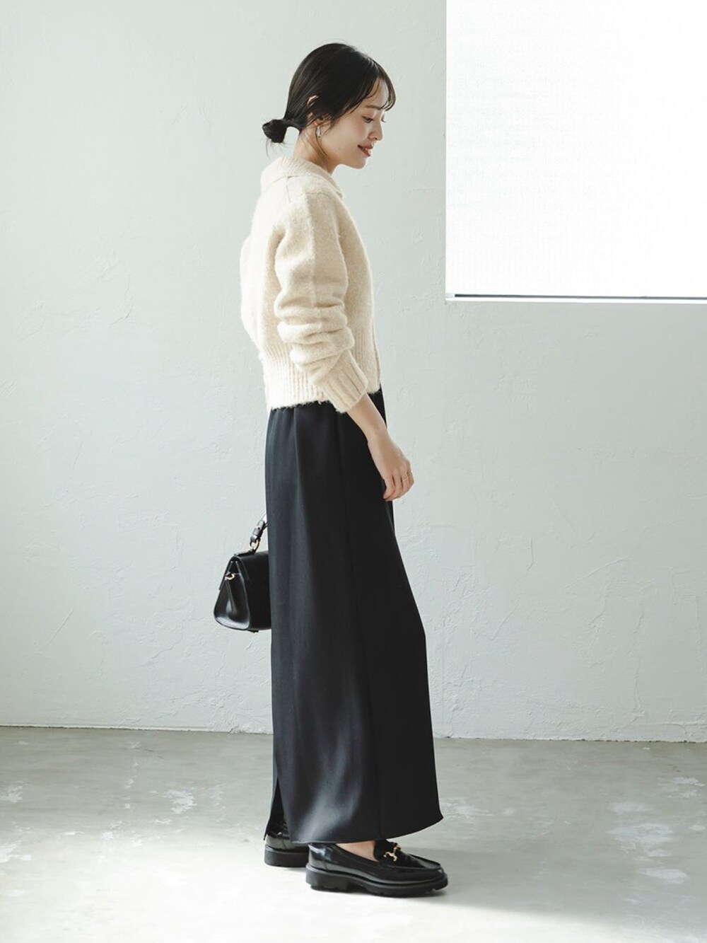 ベージュ系のカーディガン/ボレロ、ブラック系のワンピース、ブラック系のショルダーバッグを着用したレディースの秋コーディネートの2枚目の写真