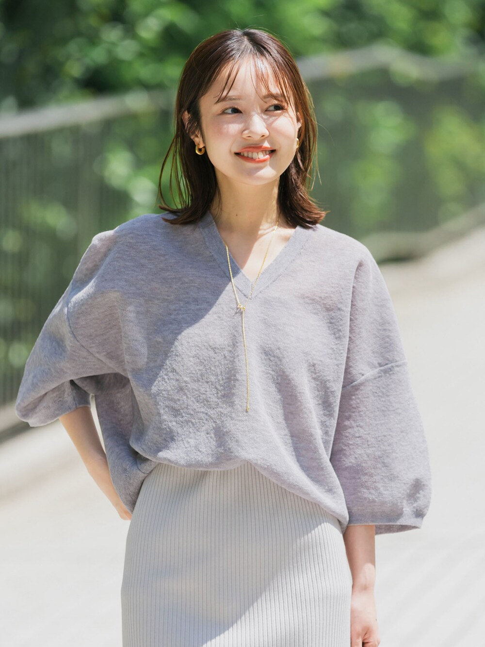 グレー系のニット/セーター、グレー系のスカートを着用したレディースの夏コーディネートの2枚目の写真