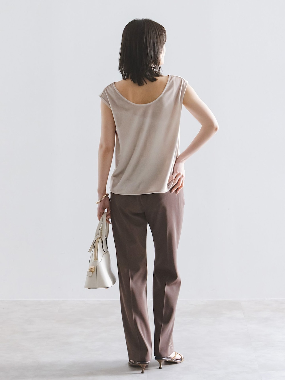 ブラウン系のスラックス、ベージュ系のTシャツ/カットソー、ホワイト系のボストンバッグを着用したレディースの夏コーディネートの3枚目の写真