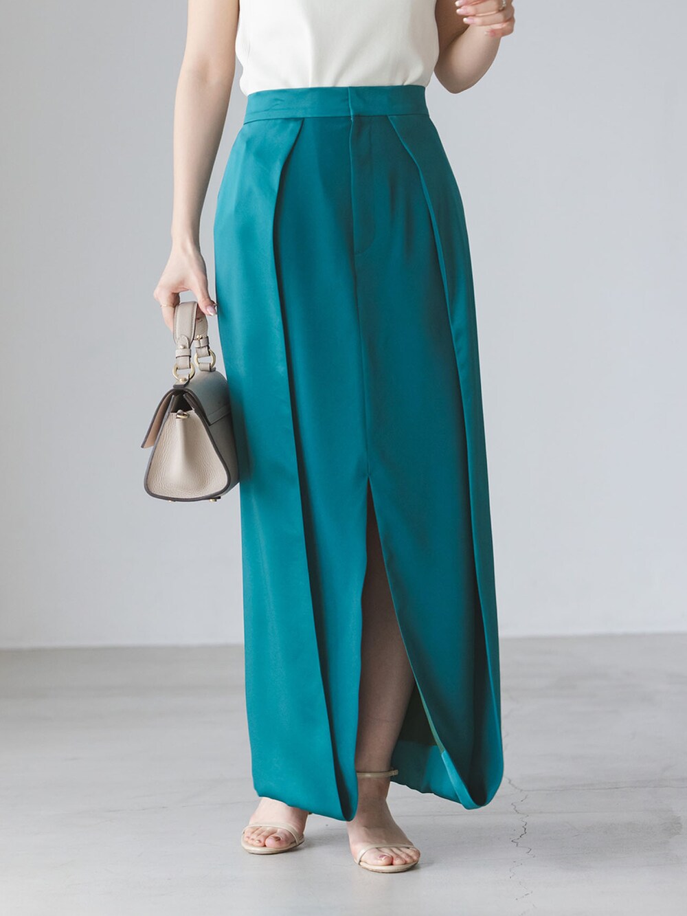 ホワイト系のタンクトップ、グリーン系のスカート、ベージュ系のショルダーバッグを着用したレディースの春コーディネートの3枚目の写真