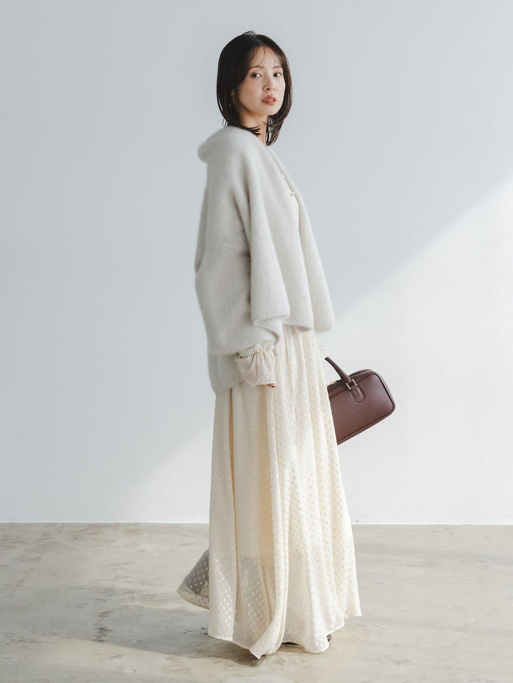 ベージュ系のワンピース、ベージュ系のカーディガン/ボレロ、ブラウン系のボストンバッグを着用したレディースの秋コーディネートの2枚目の写真