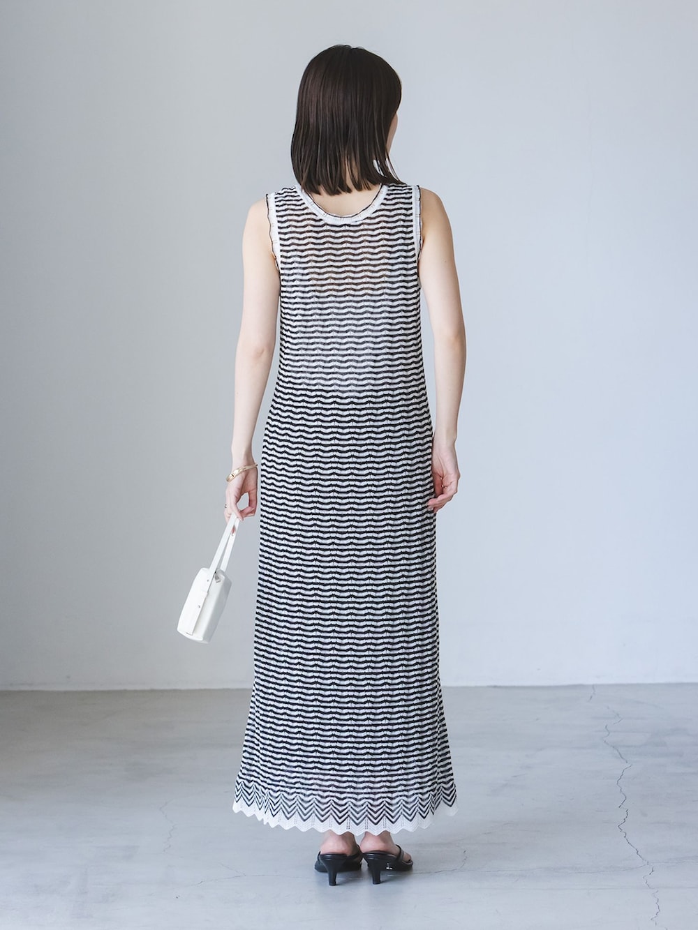 その他のワンピース、ホワイト系のショルダーバッグ、ブラック系のサンダルを着用したレディースの夏コーディネートの3枚目の写真