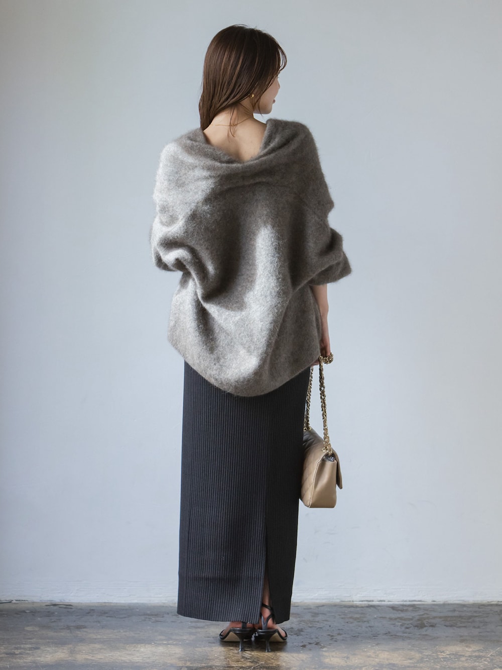 グレー系のカーディガン/ボレロ、ブラック系のスカート、ベージュ系のショルダーバッグを着用したレディースの秋コーディネートの3枚目の写真