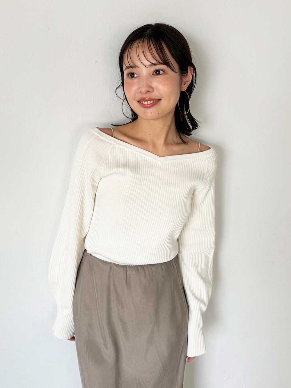 ホワイト系のニット/セーター、グレー系のスカート、ブラウン系のローファーを着用したレディースの秋コーディネートの3枚目の写真