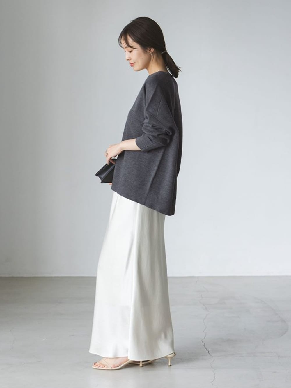 グレー系のニット/セーター、ホワイト系のスカートを着用したレディースの秋コーディネートの2枚目の写真