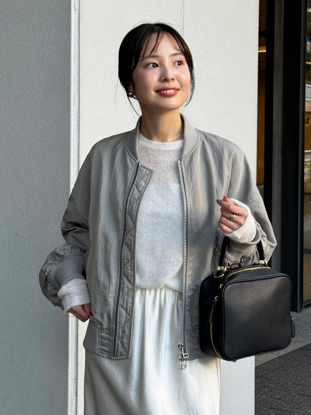 グレー系のMA-1、ホワイト系のニット/セーター、ホワイト系のスカートを着用したレディースの秋コーディネートの3枚目の写真