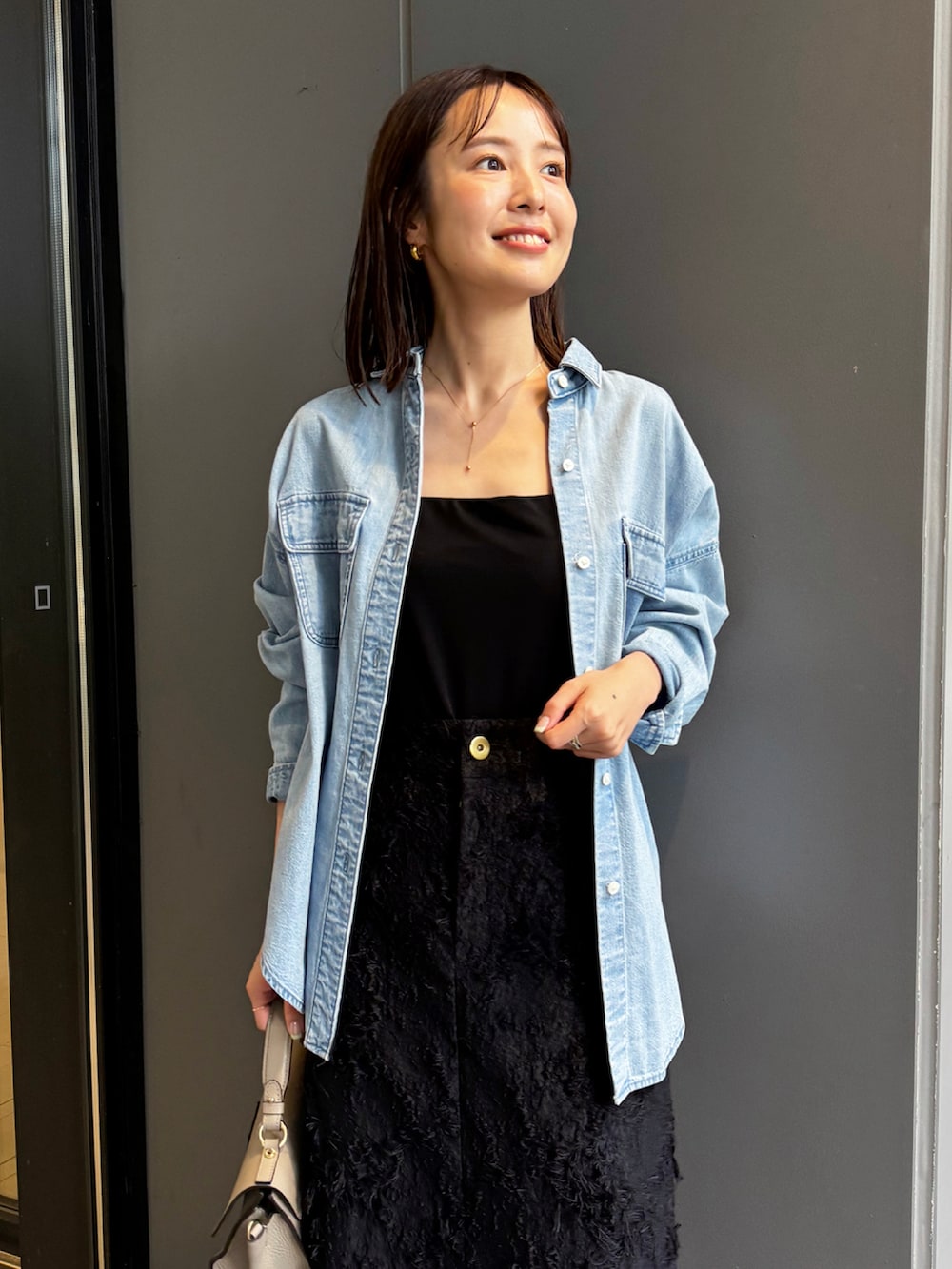 ブルー系のシャツ/ブラウス、ブラック系のスカート、グレー系のショルダーバッグを着用したレディースの秋コーディネートの3枚目の写真