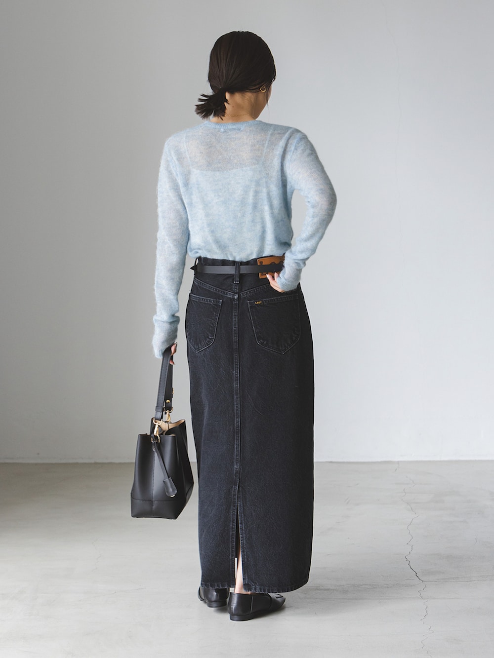 ブルー系のニット/セーター、ブラック系のデニムスカート、ブラック系のショルダーバッグを着用したレディースの秋コーディネートの3枚目の写真