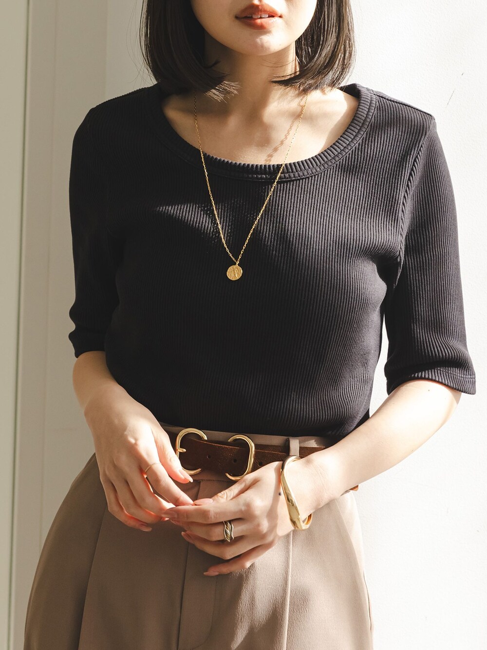 ベージュ系のスラックス、ブラック系のTシャツ/カットソー、ブラック系のボストンバッグを着用したレディースの冬コーディネートの4枚目の写真