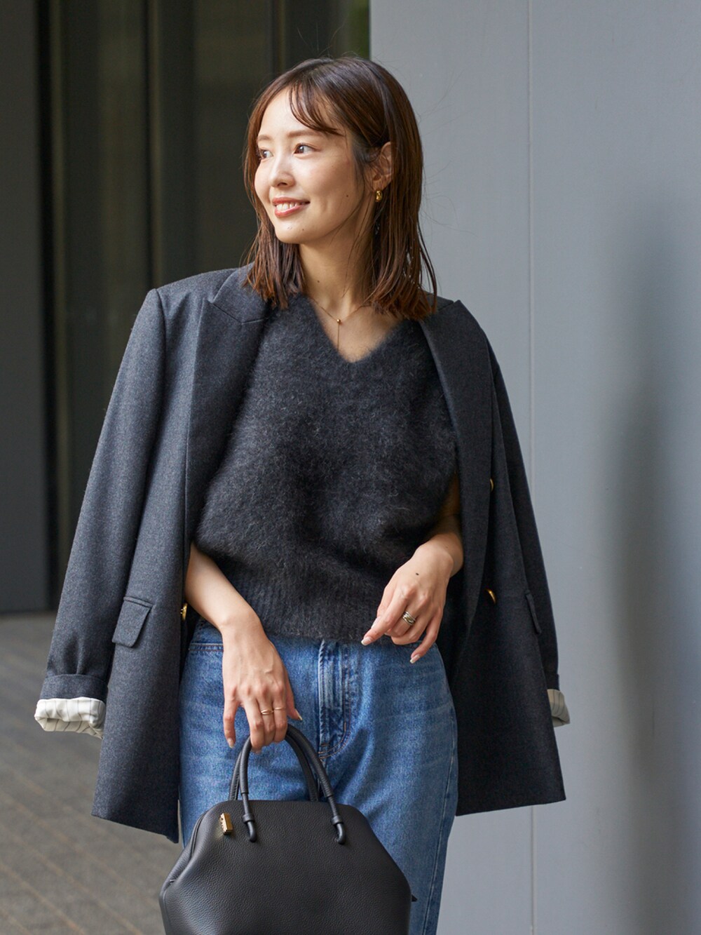 グレー系のベスト、グレー系のテーラードジャケット、ブルー系のデニムパンツを着用したレディースの秋コーディネートの4枚目の写真