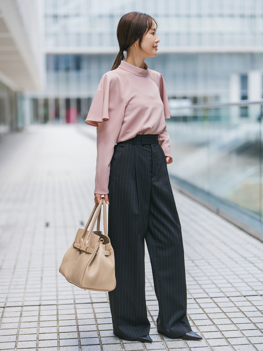 ピンク系のシャツ/ブラウス、ブルー系のスラックス、ベージュ系のショルダーバッグを着用したレディースの秋コーディネートの2枚目の写真