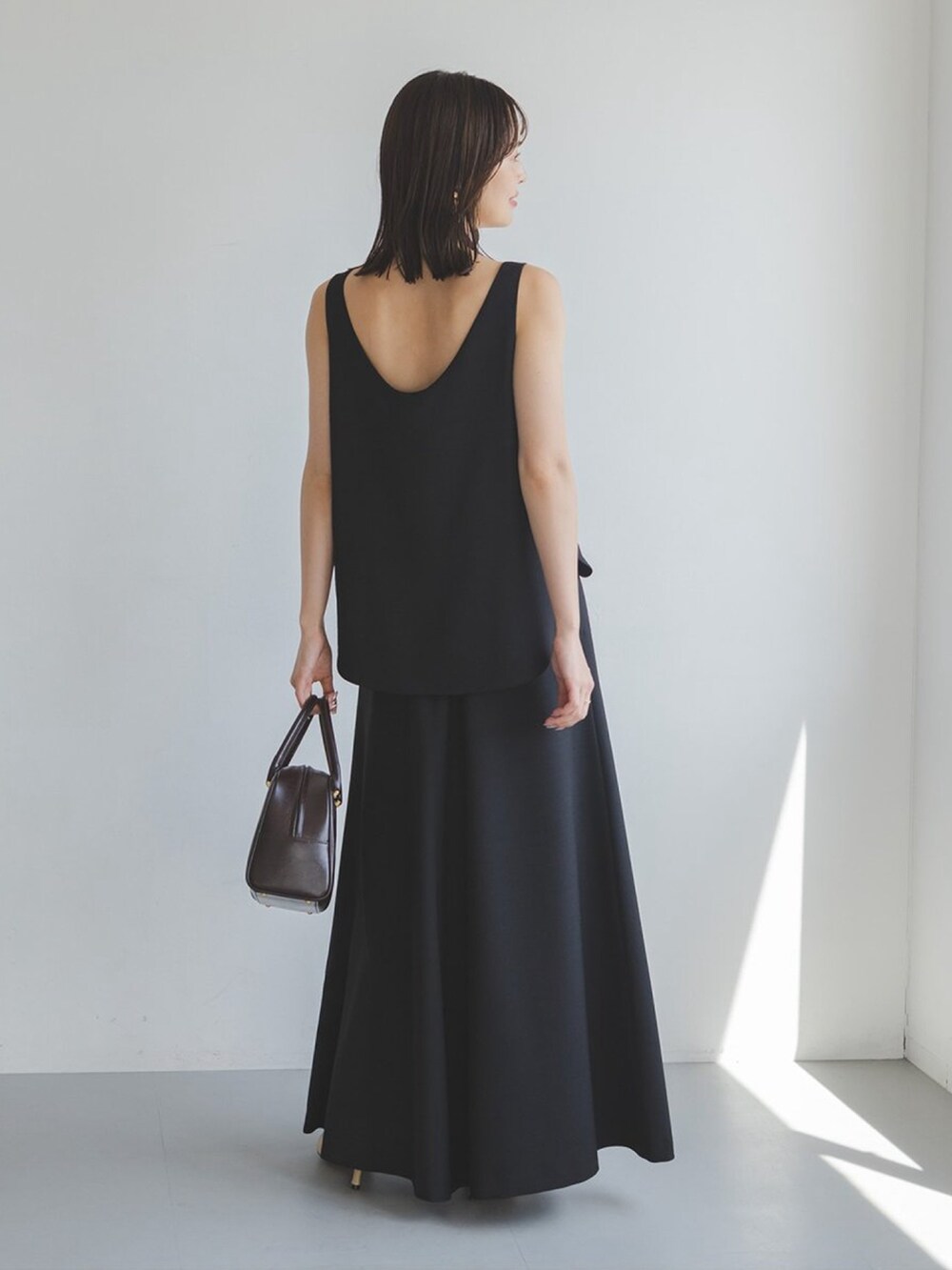 ブラック系のワンピース、ブラウン系のハンドバッグを着用したレディースの夏コーディネートの2枚目の写真