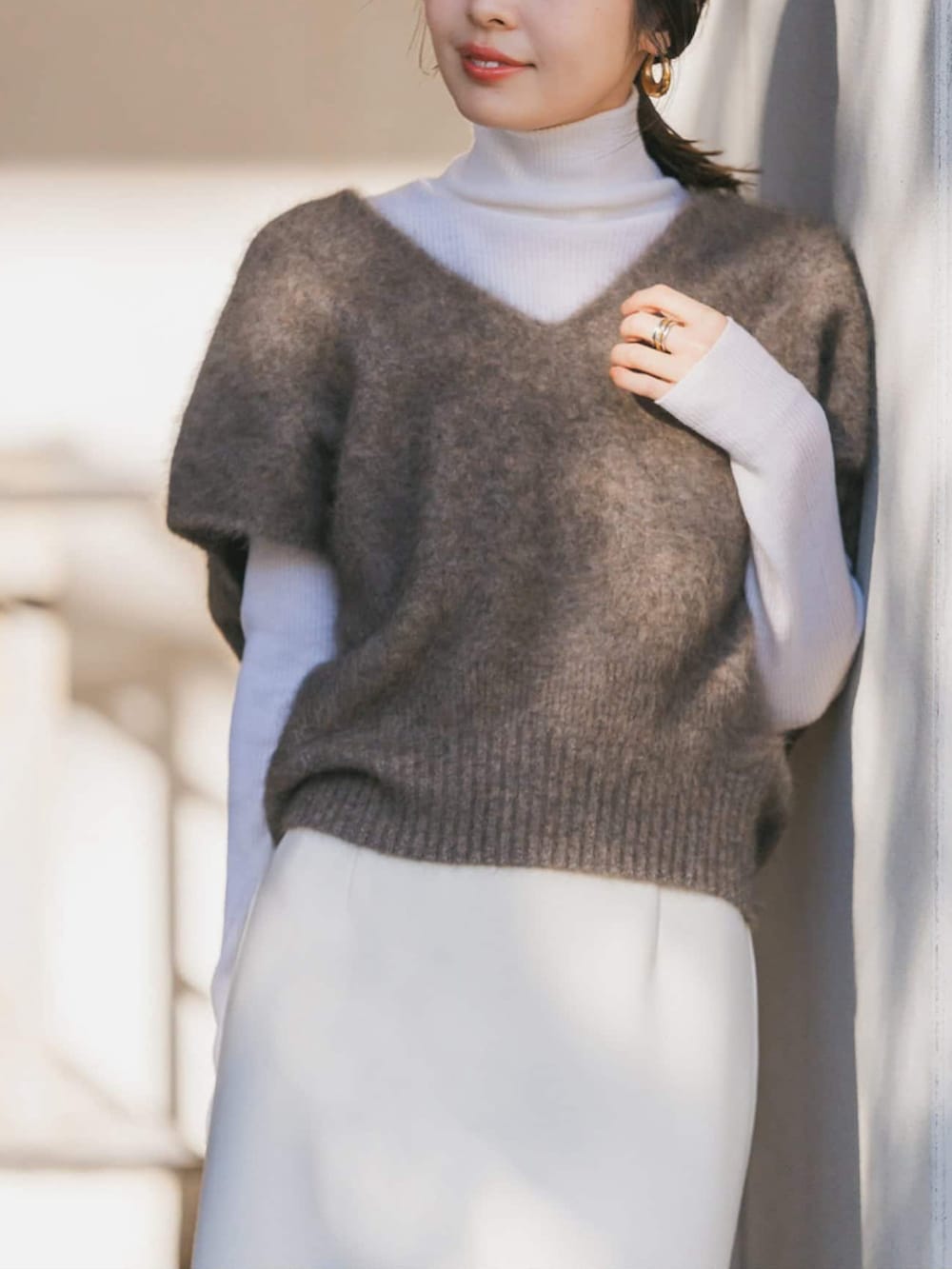 ブラウン系のベスト、ホワイト系のニット/セーター、ホワイト系のスカートを着用したレディースの冬コーディネートの3枚目の写真