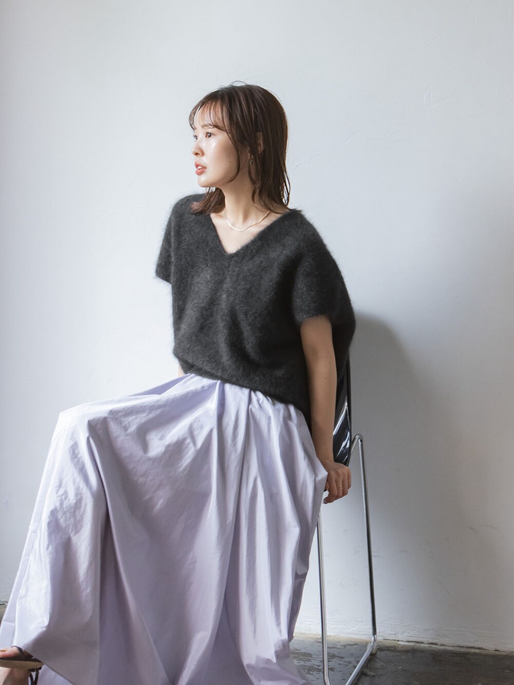 グレー系のベスト、パープル系のスカート、ブラック系のショルダーバッグを着用したレディースの秋コーディネートの2枚目の写真