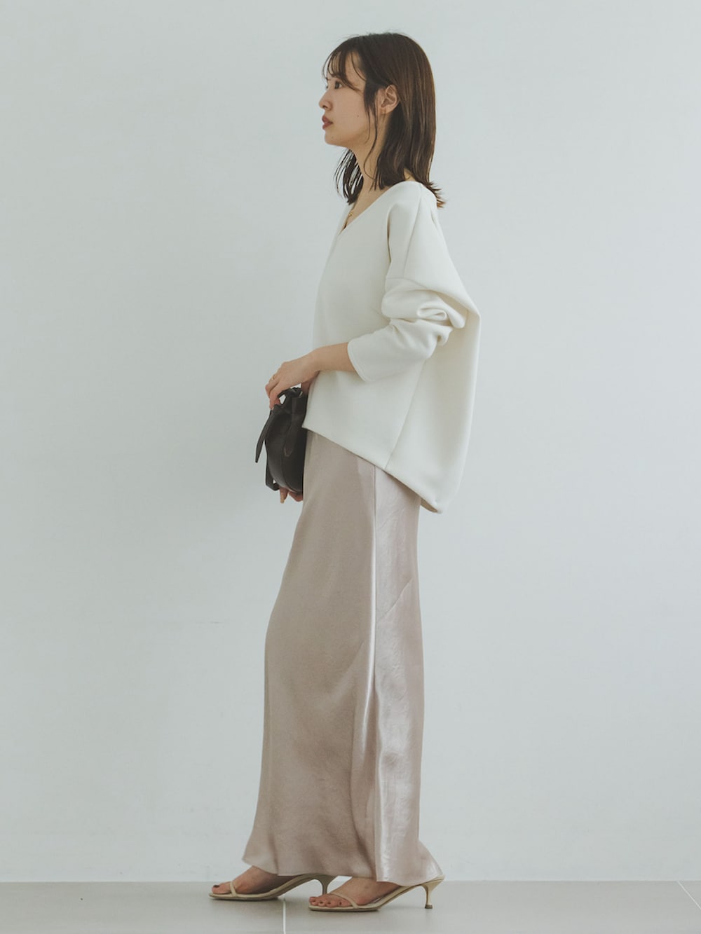 ホワイト系のスウェット、ベージュ系のスカート、ブラウン系のショルダーバッグを着用したレディースの夏コーディネートの2枚目の写真