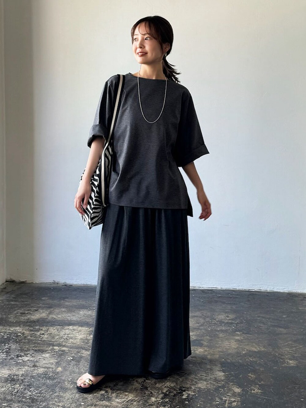 グレー系のTシャツ/カットソー、グレー系のスカート、ブラック系のトートバッグを着用したレディースの夏コーディネートの2枚目の写真