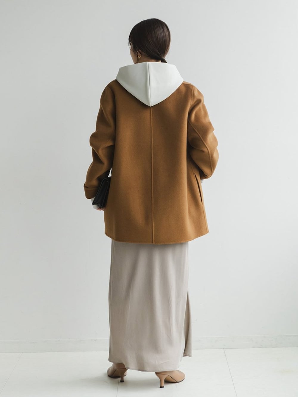 イエロー系のチェスターコート、ホワイト系のスウェット、グレー系のスカートを着用したレディースの秋コーディネートの2枚目の写真