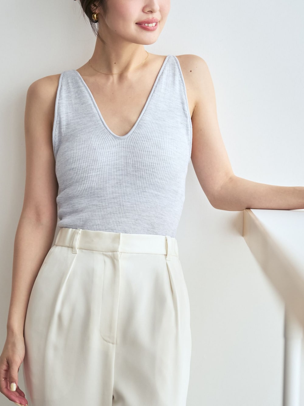 ホワイト系のスラックス、ベージュ系のパンプス、ゴールド系のネックレスを着用したレディースの夏コーディネートの6枚目の写真