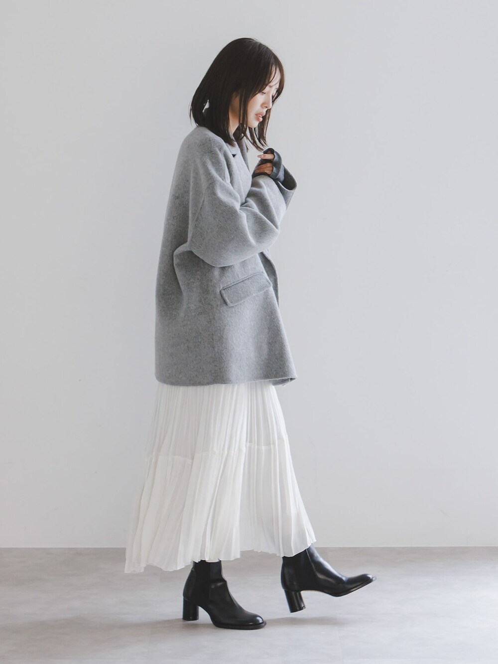 グレー系のその他アウター、ホワイト系のスカート、グレー系のTシャツ/カットソーを着用したレディースの秋コーディネートの2枚目の写真