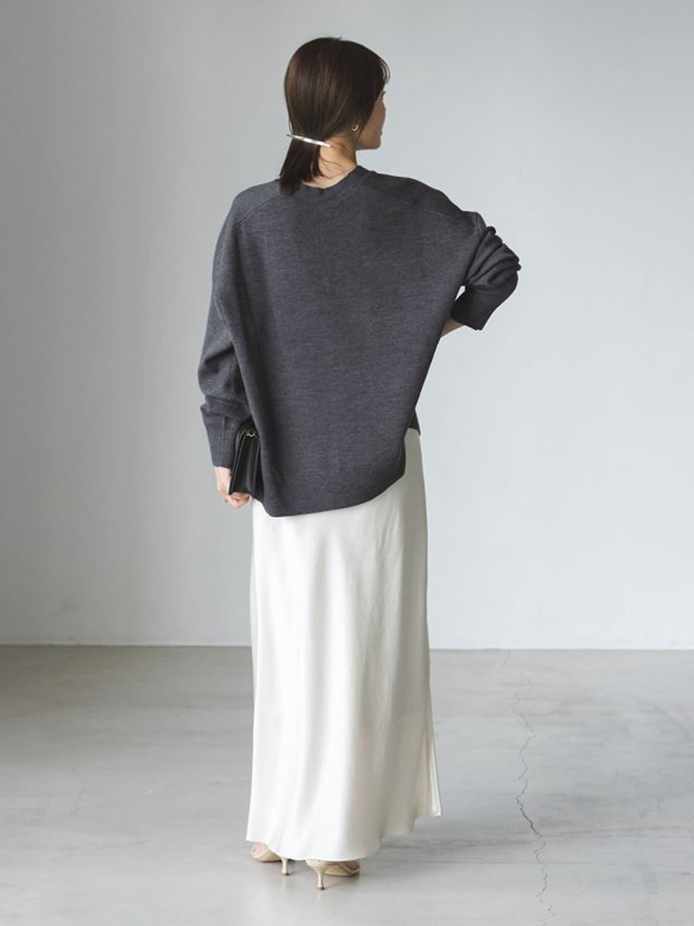 グレー系のニット/セーター、ホワイト系のスカートを着用したレディースの秋コーディネートの3枚目の写真