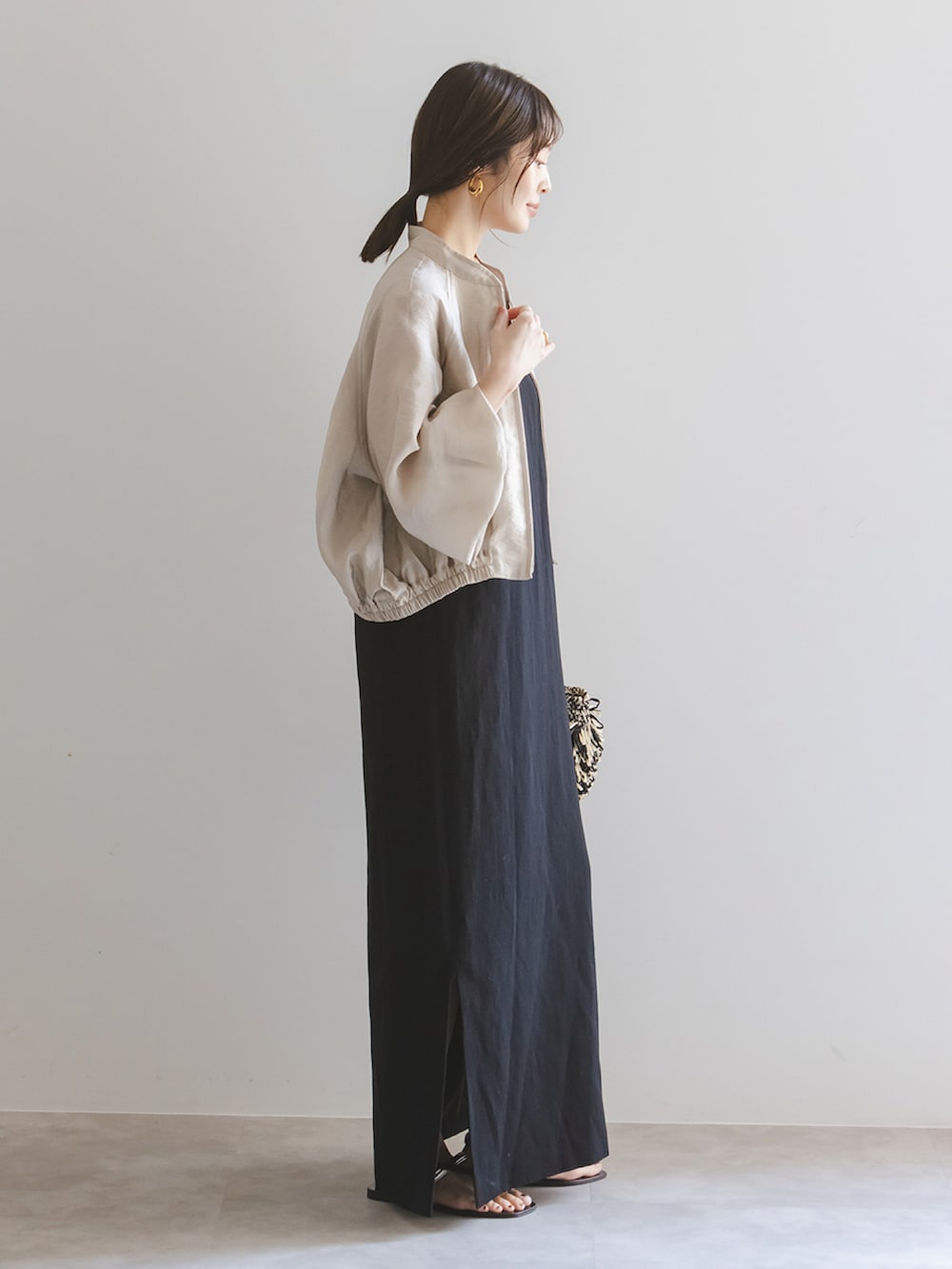 ブラック系のワンピース、ベージュ系のブルゾン、ブラック系のショルダーバッグを着用したレディースの春コーディネートの2枚目の写真