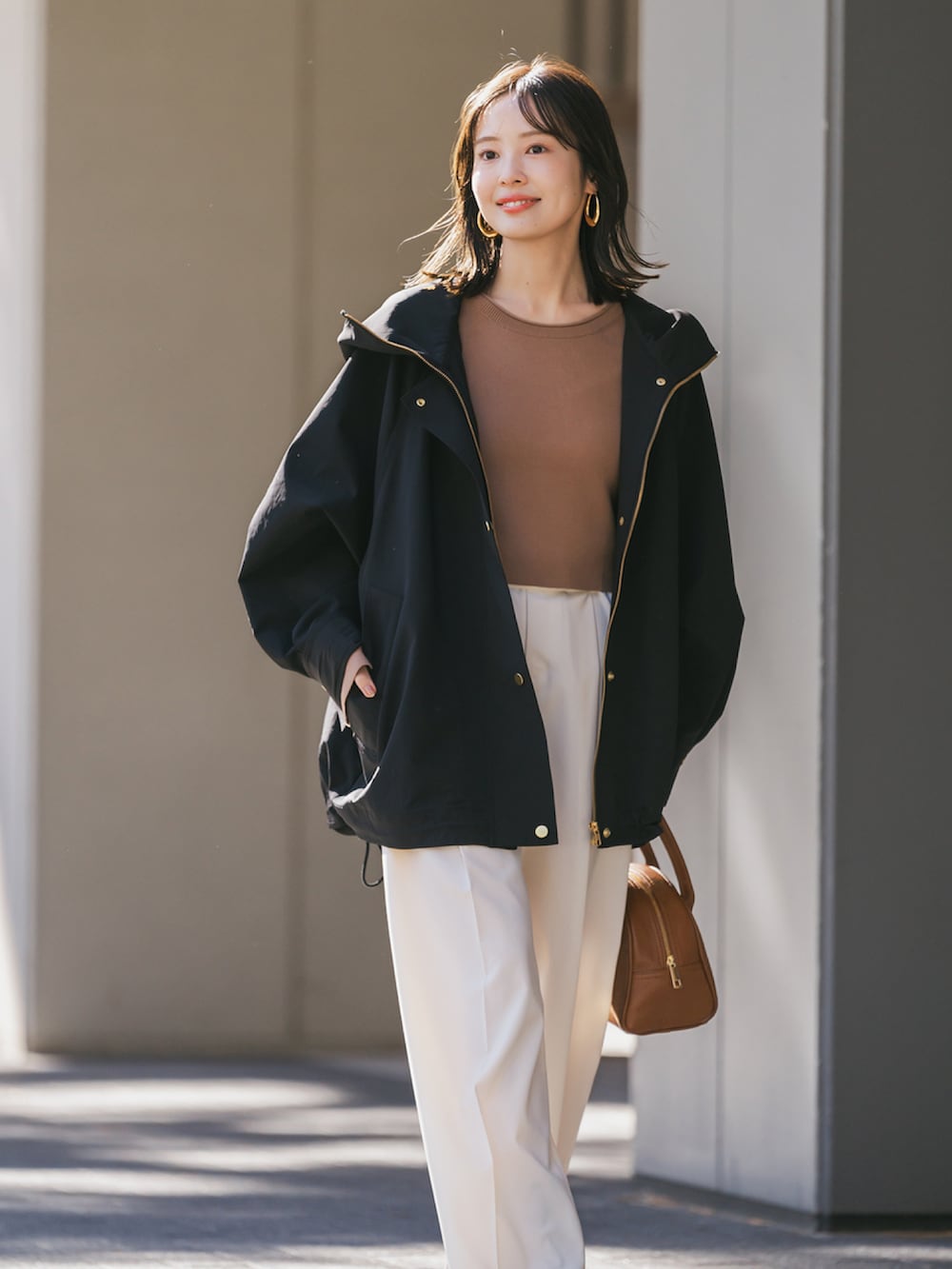 ブラック系のその他アウター、イエロー系のニット/セーター、ベージュ系のスラックスを着用したレディースの冬コーディネートの2枚目の写真