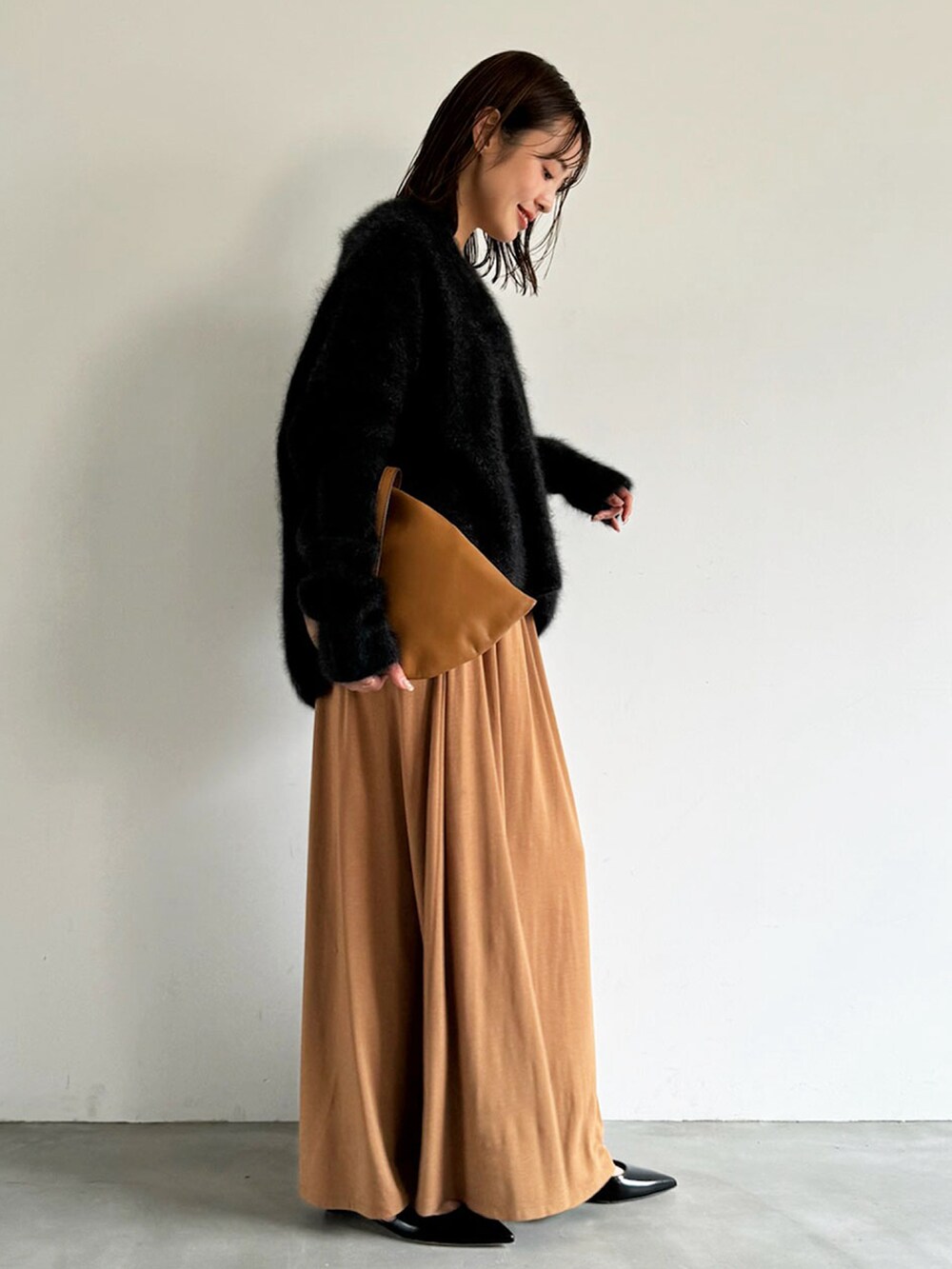 グレー系のニット/セーター、イエロー系のスカート、ブラウン系のショルダーバッグを着用したレディースの秋コーディネートの2枚目の写真