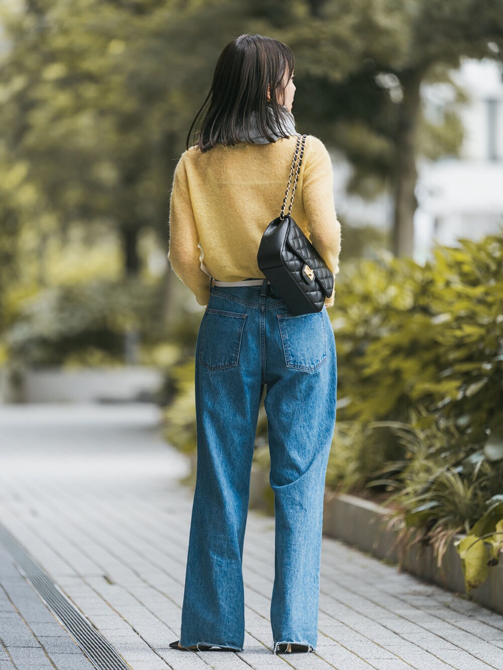 イエロー系のニット/セーター、ブラック系のショルダーバッグ、ブルー系のデニムパンツを着用したレディースの秋コーディネートの2枚目の写真