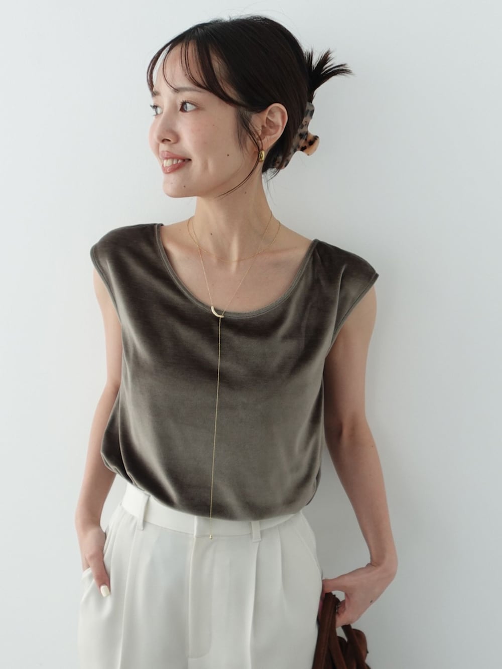 ホワイト系のスラックス、グリーン系のTシャツ/カットソー、ブラウン系のハンドバッグを着用したレディースの夏コーディネートの5枚目の写真