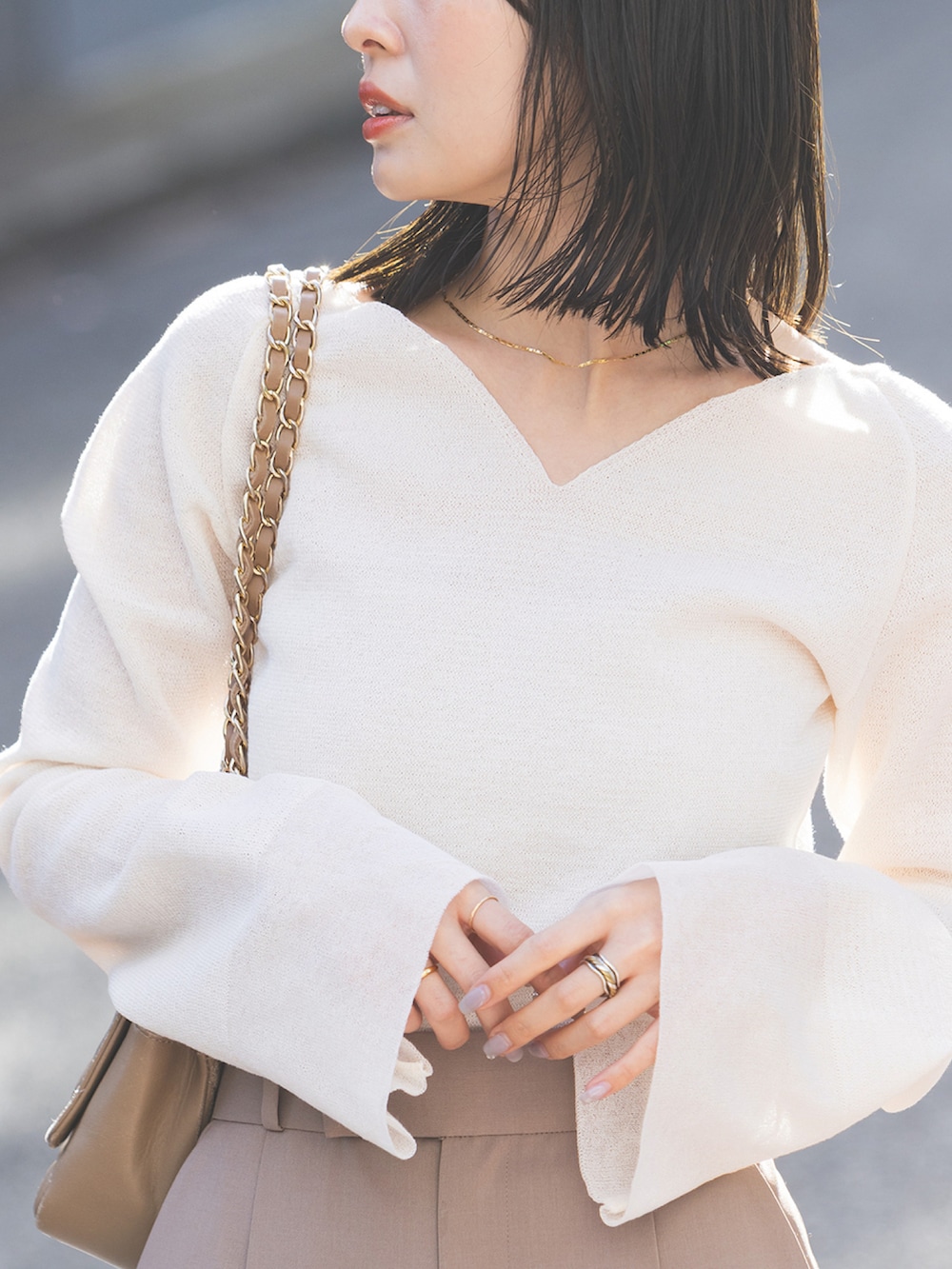 ホワイト系のニット/セーター、ブラウン系のスラックス、ベージュ系のショルダーバッグを着用したレディースの春コーディネートの3枚目の写真