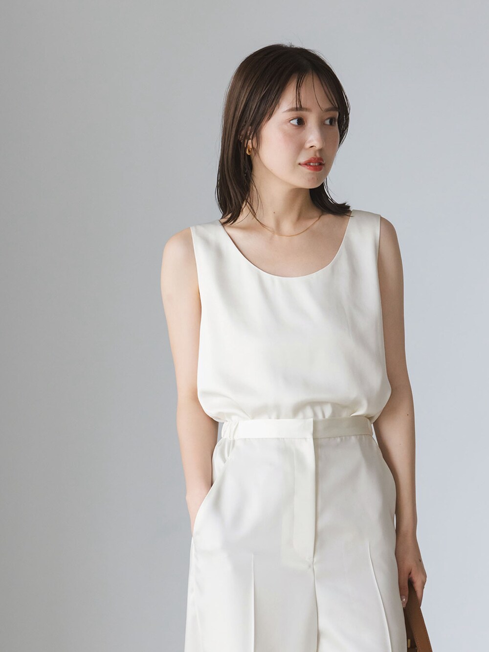 ブラウン系のカーディガン/ボレロ、ホワイト系のタンクトップ、ホワイト系のスラックスを着用したレディースの秋コーディネートの3枚目の写真