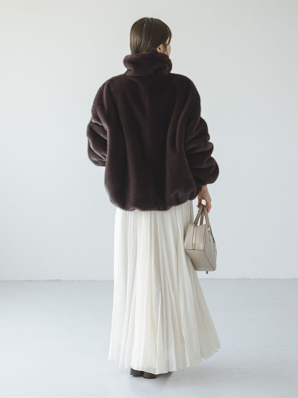 ブラウン系のその他アウター、ホワイト系のスカート、ベージュ系のショルダーバッグを着用したレディースの冬コーディネートの3枚目の写真