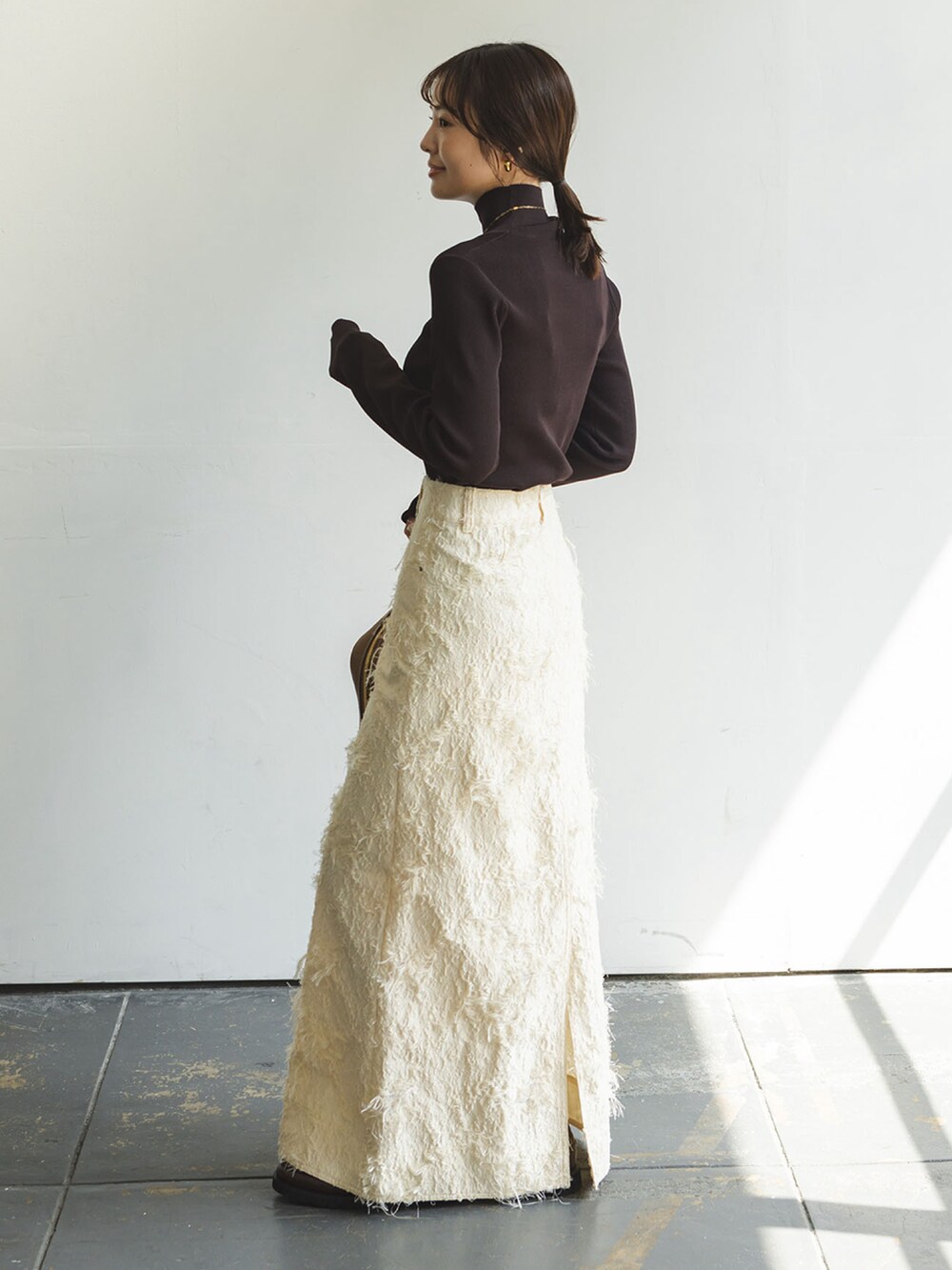 ブラウン系のニット/セーター、ベージュ系のスカート、イエロー系のショルダーバッグを着用したレディースの秋コーディネートの2枚目の写真