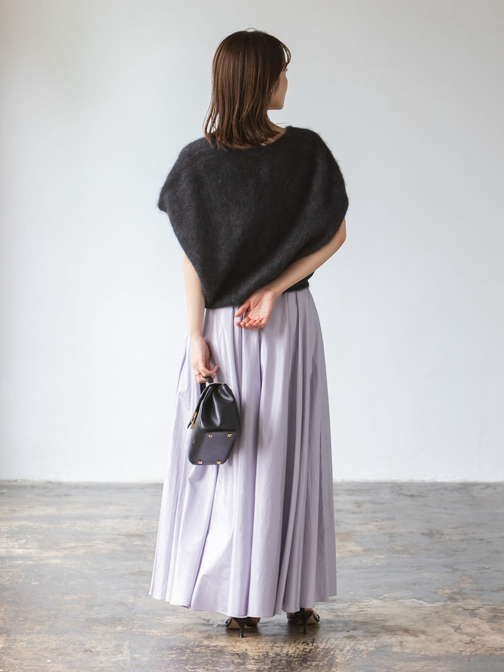 グレー系のベスト、パープル系のスカート、ブラック系のショルダーバッグを着用したレディースの秋コーディネートの3枚目の写真