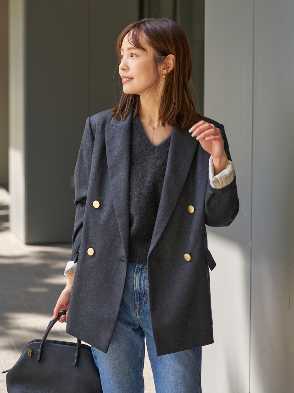 グレー系のベスト、グレー系のテーラードジャケット、ブルー系のデニムパンツを着用したレディースの秋コーディネートの3枚目の写真