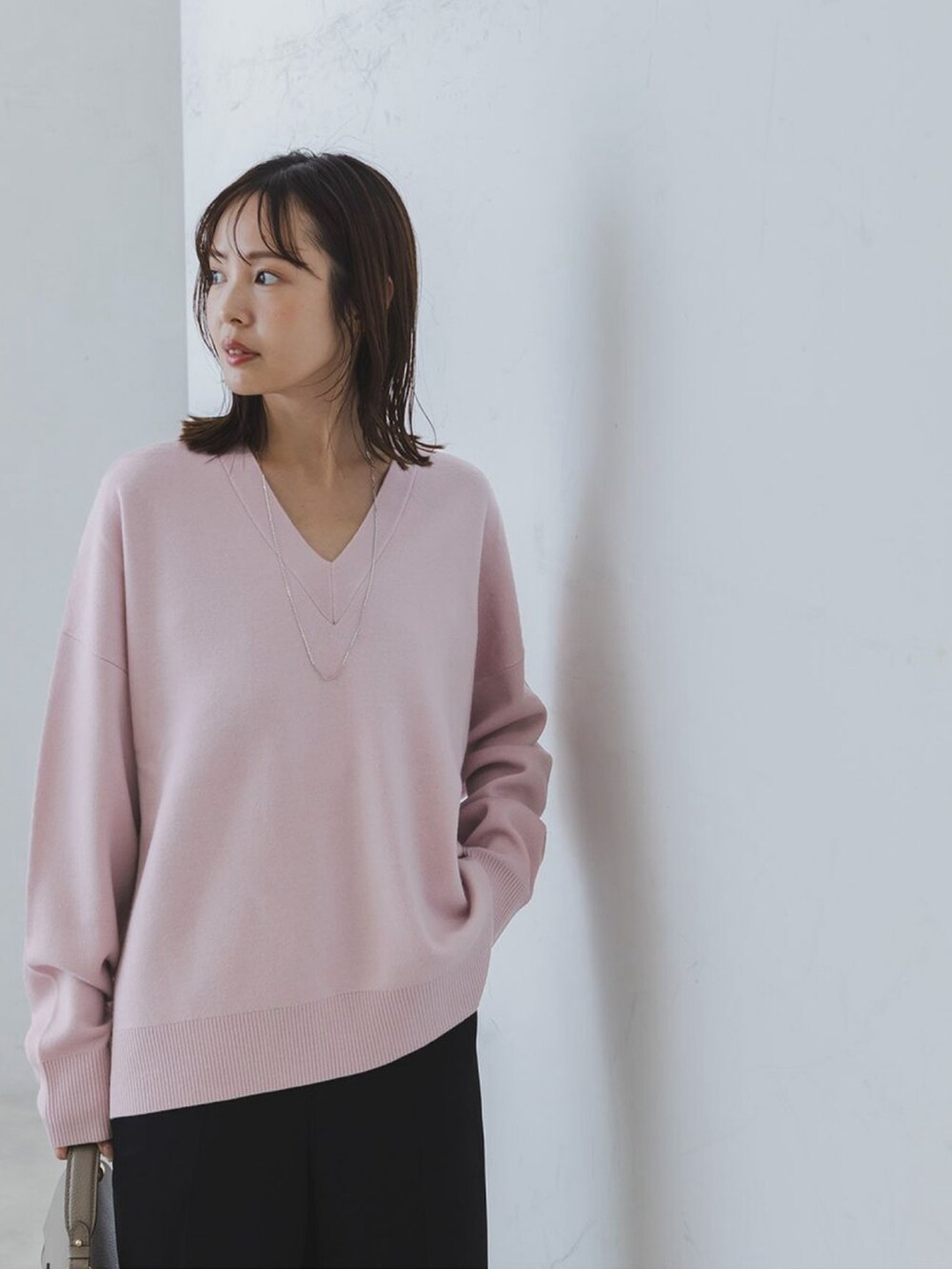 ピンク系のニット/セーター、ブラック系のスラックス、グレー系のショルダーバッグを着用したレディースの秋コーディネートの2枚目の写真