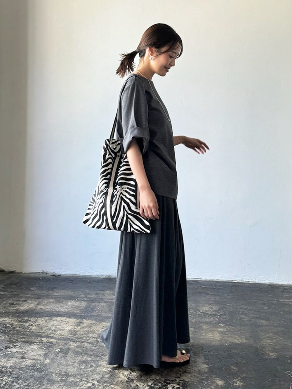グレー系のTシャツ/カットソー、グレー系のスカート、ブラック系のトートバッグを着用したレディースの夏コーディネートの3枚目の写真