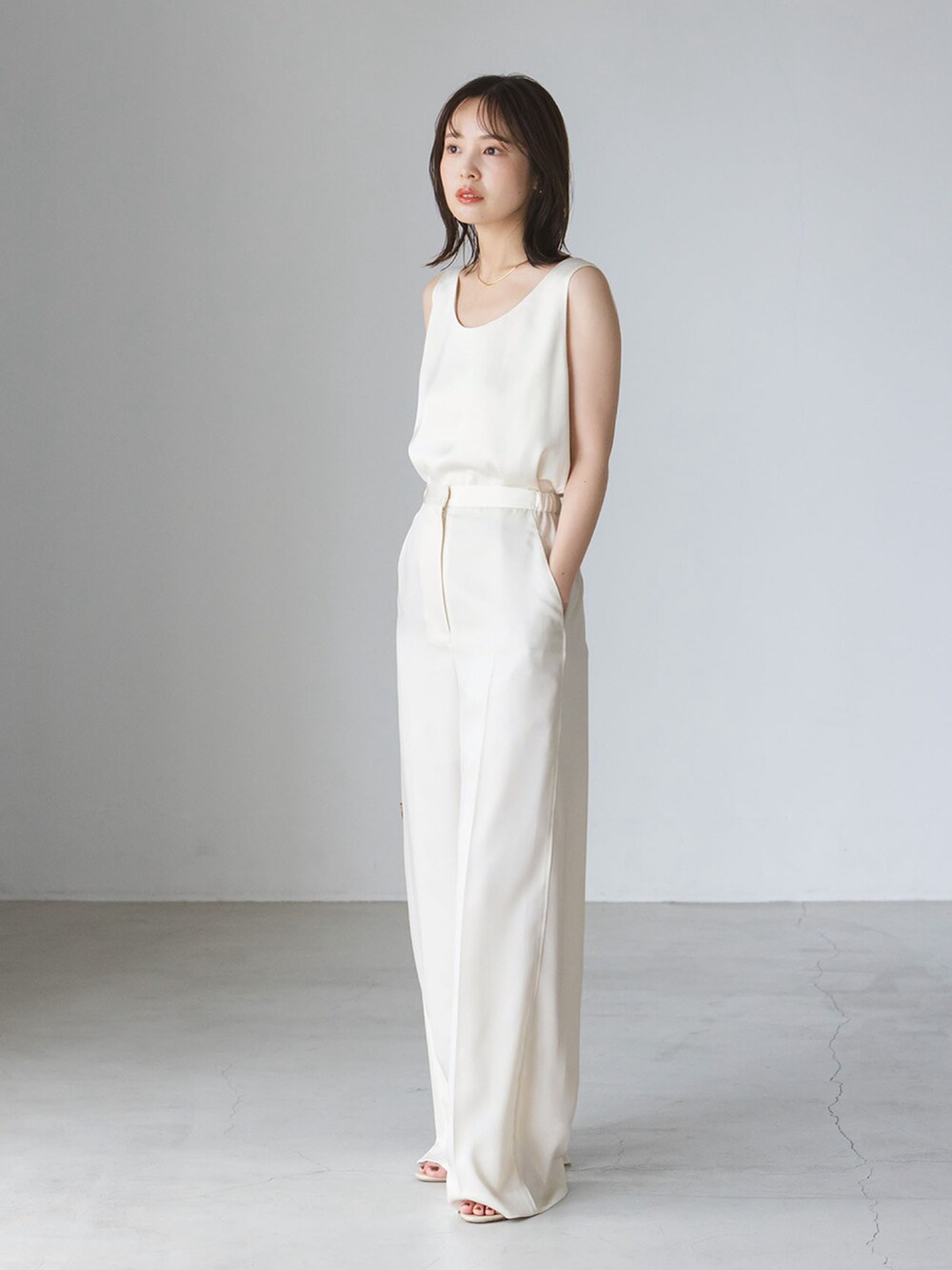 ブラウン系のカーディガン/ボレロ、ホワイト系のタンクトップ、ホワイト系のスラックスを着用したレディースの秋コーディネートの2枚目の写真