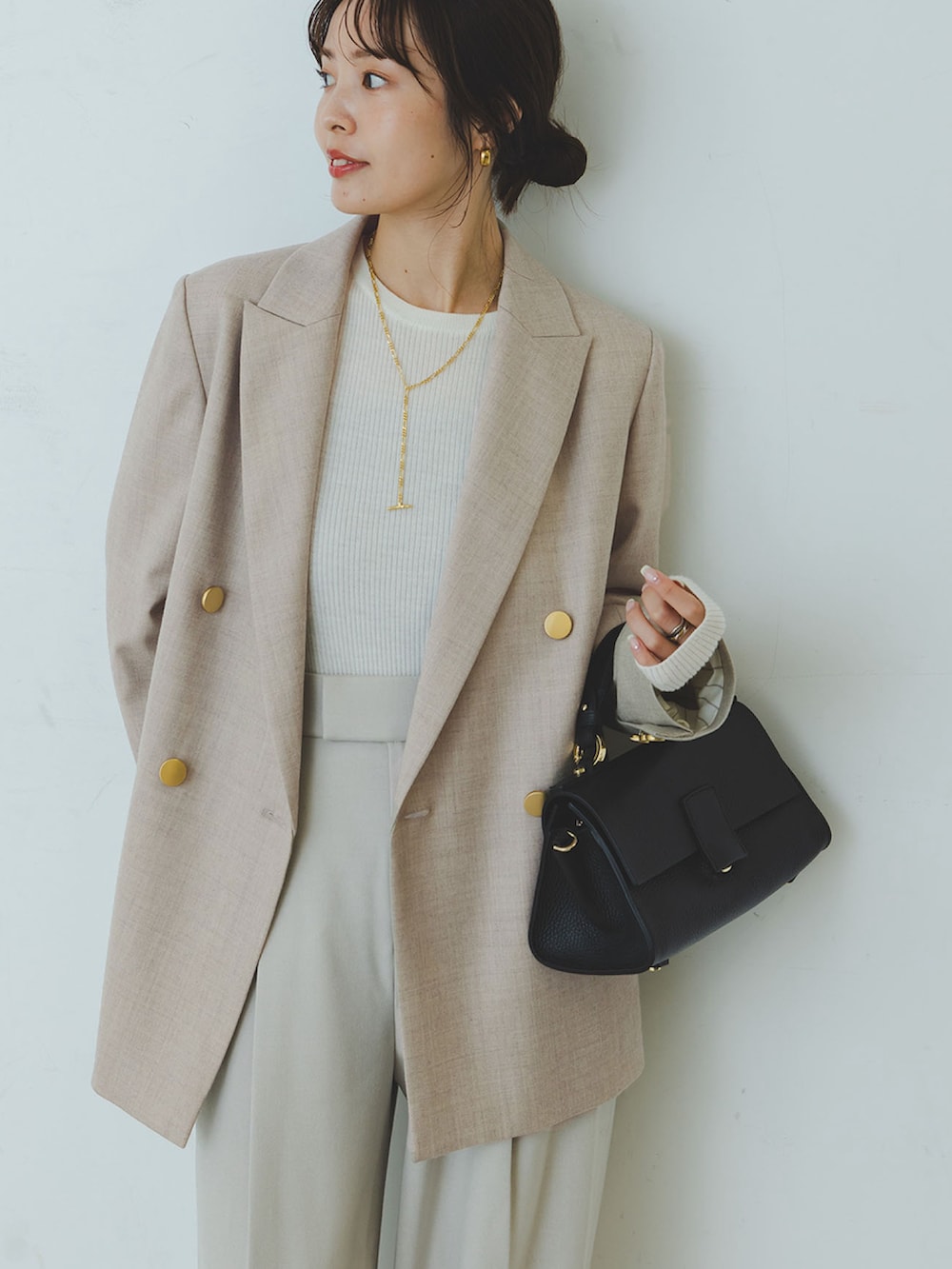ホワイト系のニット/セーター、ベージュ系のテーラードジャケット、ベージュ系のスラックスを着用したレディースの秋コーディネートの3枚目の写真
