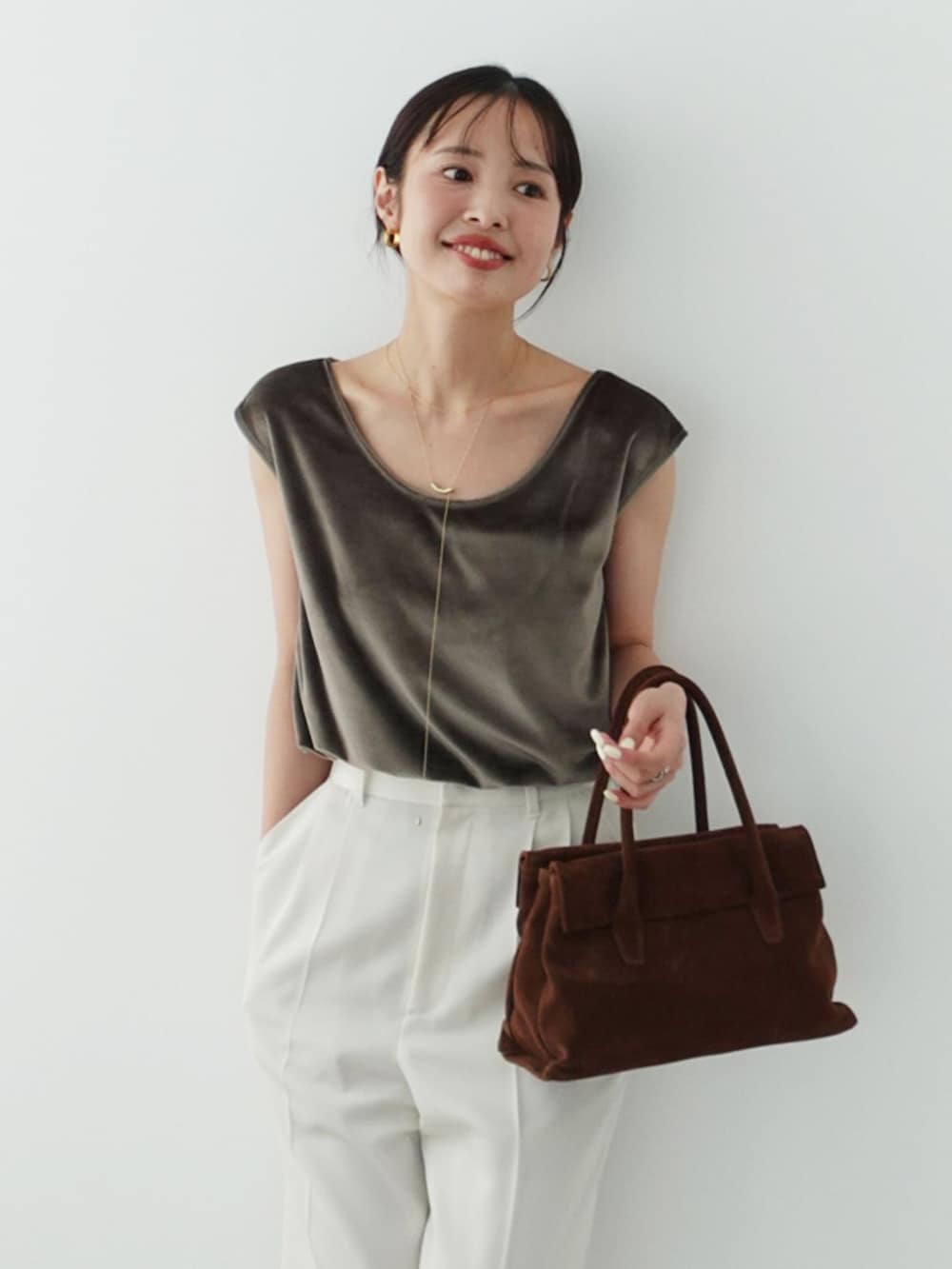 ホワイト系のスラックス、グリーン系のTシャツ/カットソー、ブラウン系のハンドバッグを着用したレディースの夏コーディネートの9枚目の写真