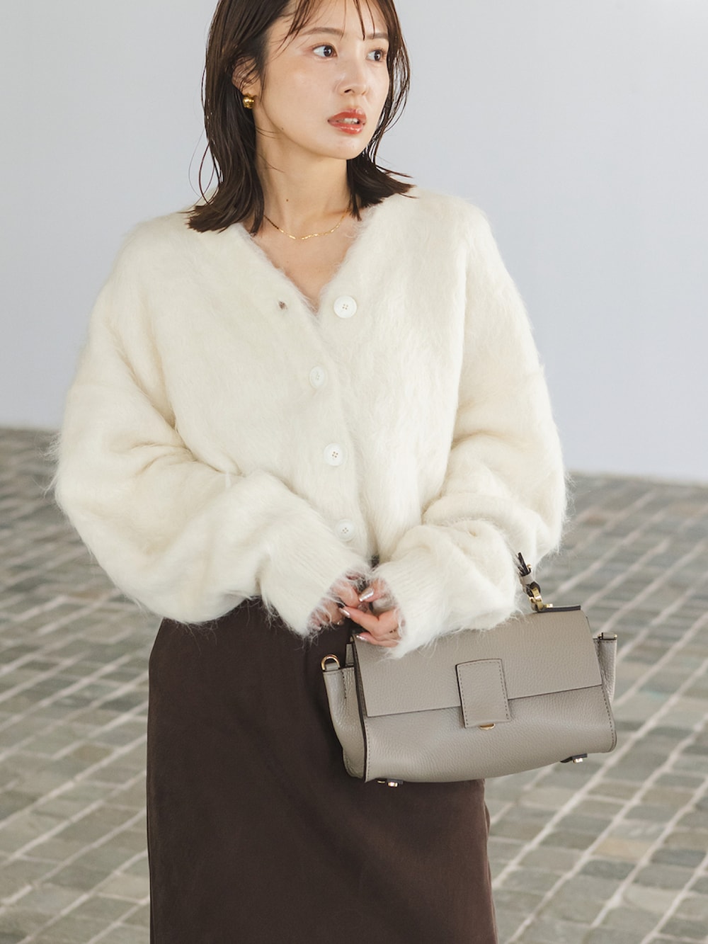 ホワイト系のカーディガン/ボレロ、ブラウン系のスカート、グレー系のショルダーバッグを着用したレディースの秋コーディネートの2枚目の写真