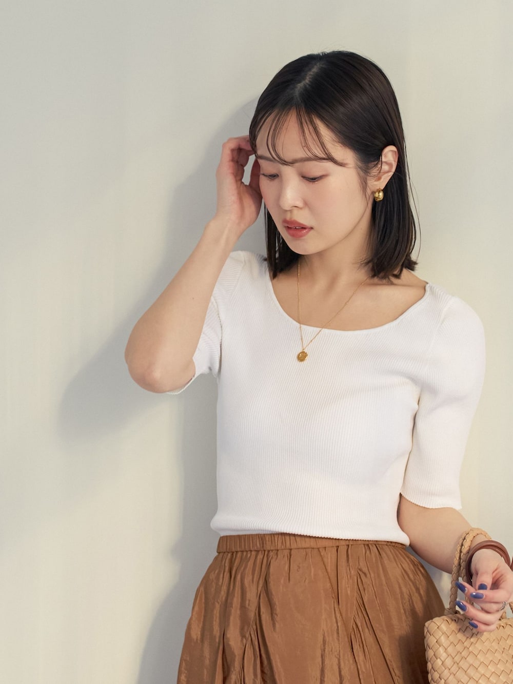 イエロー系のスカート、ホワイト系のニット/セーター、ベージュ系のハンドバッグを着用したレディースの夏コーディネートの6枚目の写真