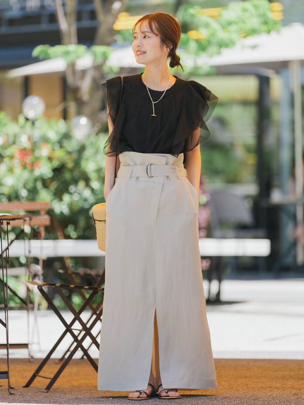 ブラック系のシャツ/ブラウス、ベージュ系のスカート、ブラック系のサンダルを着用したレディースの夏コーディネートの2枚目の写真