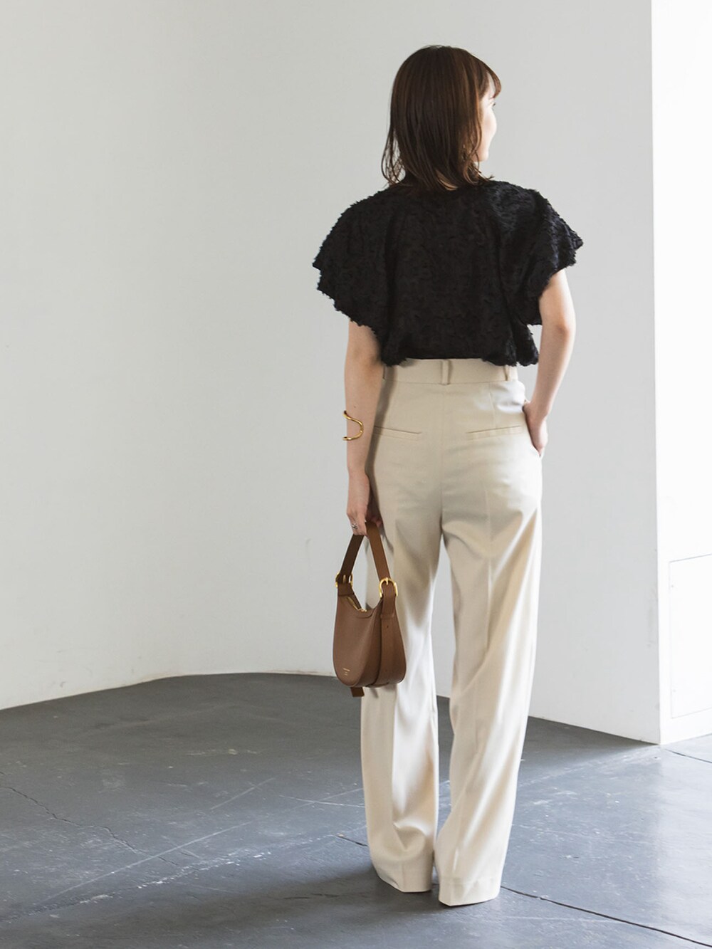 ベージュ系のスラックス、ブラック系のシャツ/ブラウス、ベージュ系のサンダルを着用したレディースの夏コーディネートの2枚目の写真